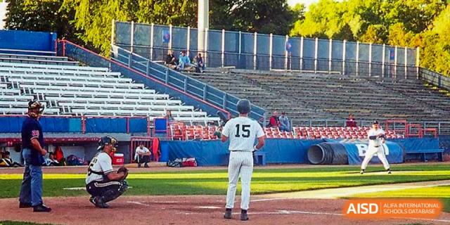 Baseball player (No. 15) on a field in front of stadium seats at Wuhan Hongshan High School International Department.