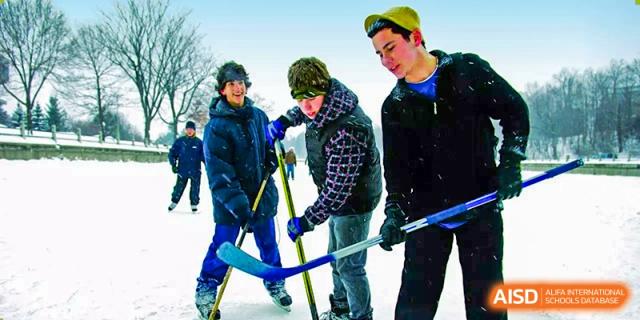 Playing ice hockey outdoors in snow. Wuhan Hongshan High School International Department. Three young people in winter gear with sticks. Fun winter sports activity on campus.