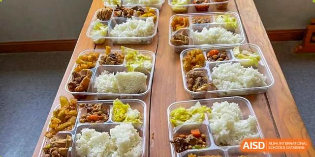 Several takeaway containers with meals of rice and various dishes, representing the student dining options at Wuhan Hongshan High School International Department.