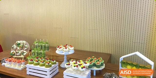 A dessert display with cupcakes and small tarts decorated with fruit, prepared for a celebration or event at Wuhan Hongshan High School International Department.