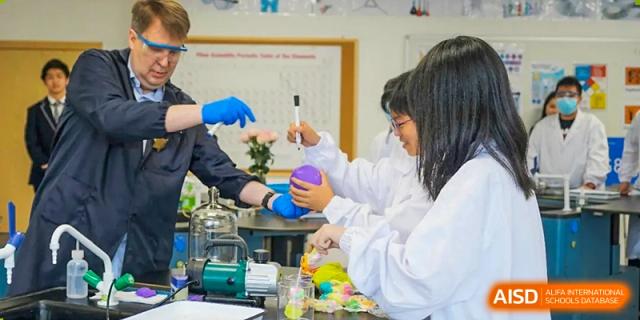 Students from BASIS International School Guangzhou wearing lab coats and conducting a science experiment with chemicals and equipment.