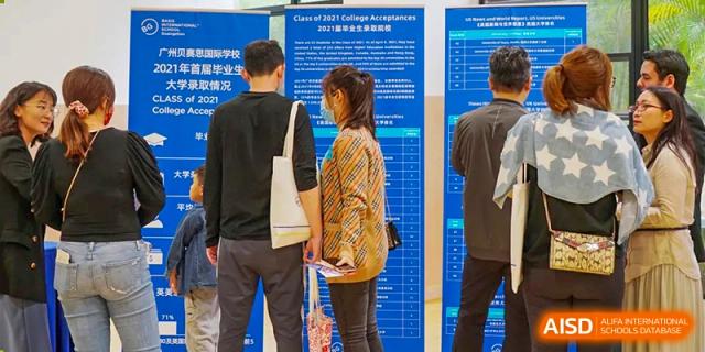 Adults looking at a large poster board display during an event or conference at BASIS International School Guangzhou.
