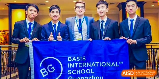 Three male students from BASIS International School Guangzhou wearing suits and holding a blue banner for BASIS International School Guangzhou.