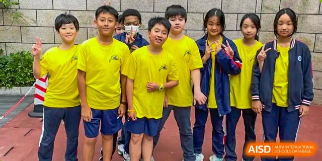 A group of male and female students from BASIS International School Guangzhou wearing yellow and blue uniforms.