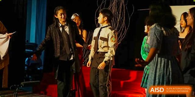 A male student from BASIS International School Guangzhou in a uniform and a spotlight performing on a stage.