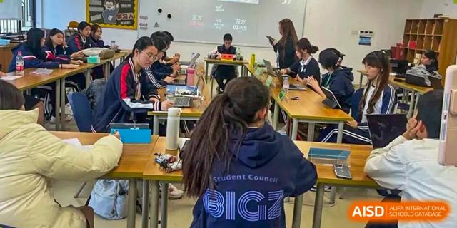 Students from BASIS International School Guangzhou working in a busy classroom, one wearing a Student Council shirt.