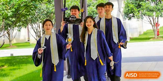 A group of graduating students from BASIS International School Guangzhou in blue gowns and stoles, taking a selfie together.