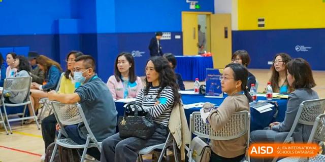 A female student from BASIS International School Guangzhou sitting and smiling at a table during an event.