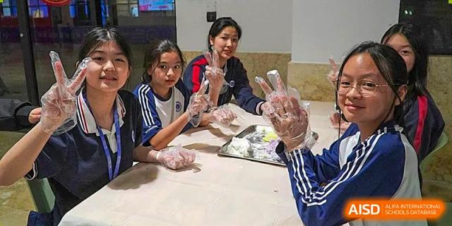 A group of female students from BASIS International School Guangzhou making dumplings or dough while wearing plastic gloves.