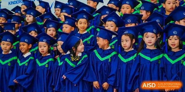 A close-up of very young students from BASIS International School Guangzhou in blue graduation caps and gowns.