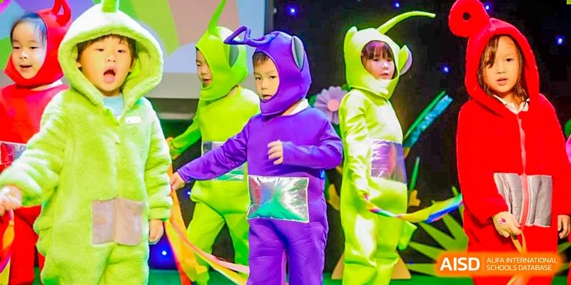 A young child from BASIS International School Guangzhou dressed in a brightly colored, purple and neon-green costume with a hood, possibly performing.