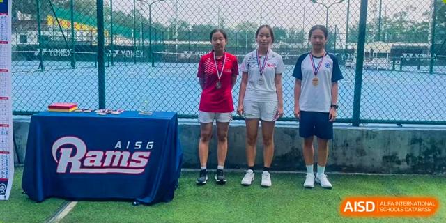 Two female students from BASIS International School Guangzhou wearing medals and standing on a podium after a sports competition.