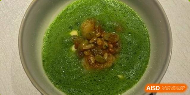 A bowl of vibrant green soup topped with squash seeds and other toppings, served at BASIS International School Guangzhou.