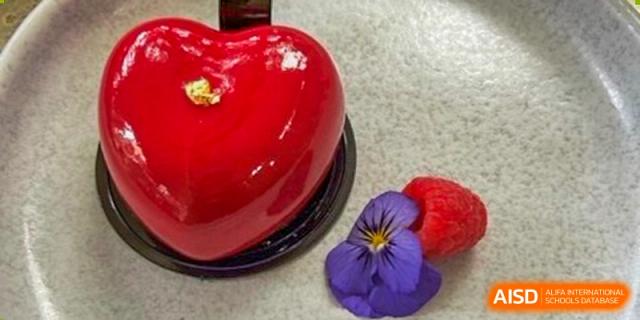 A red, heart-shaped glazed dessert garnished with a purple flower from BASIS International School Guangzhou.