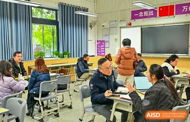 Chengdu No.7 High School International Department students and adults sitting at tables during a meeting or discussion in a bright room.