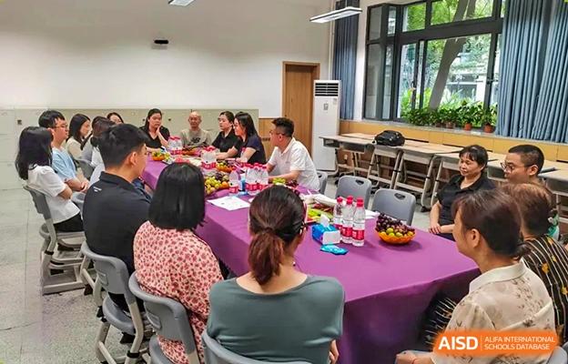 Group of Chengdu No.7 High School International Department students or parents sitting at tables decorated with colorful cloths during a school event or gathering.