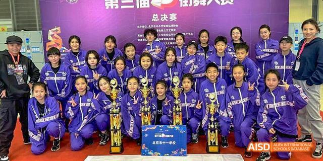 A group of students from Beijing National Day School International Department posing with trophies and awards.