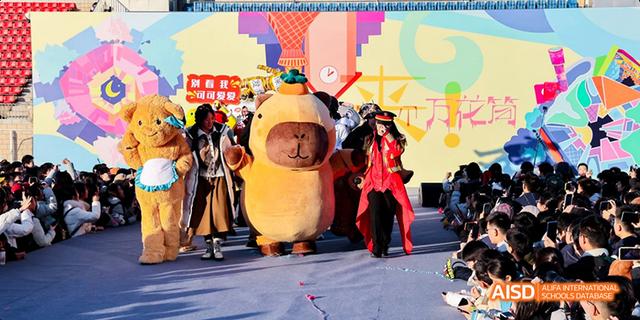 Students from Beijing National Day School International Department dressed in costumes, performing a dance or play on a stage.