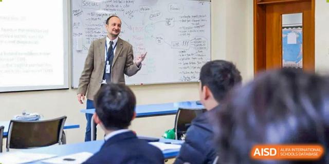 A teacher from Harrow International School Beijing (AISL Beijing) lectures to a classroom of students in front of a whiteboard.