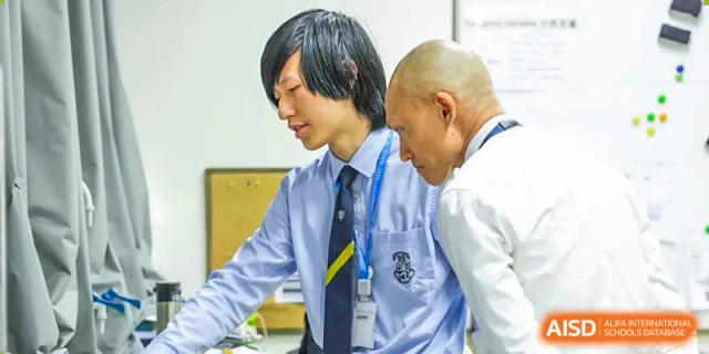 A teacher guides two male students from Harrow International School Beijing (AISL Beijing) during a hands-on lab session.