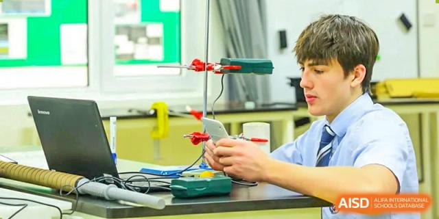 A male student from Harrow International School Beijing (AISL Beijing) is working with lab equipment and a laptop in a science experiment.