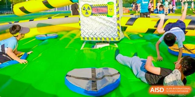 A student from Harrow International School Beijing (AISL Beijing) is playing on a large, inflatable obstacle course.