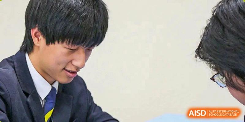 A student from Harrow International School Beijing (AISL Beijing) is concentrating on a task during a school competition or event.