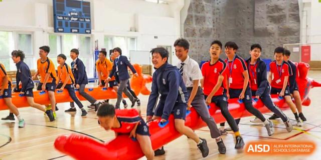 Male students from Harrow International School Beijing (AISL Beijing) are playing a basketball game in the school gymnasium.