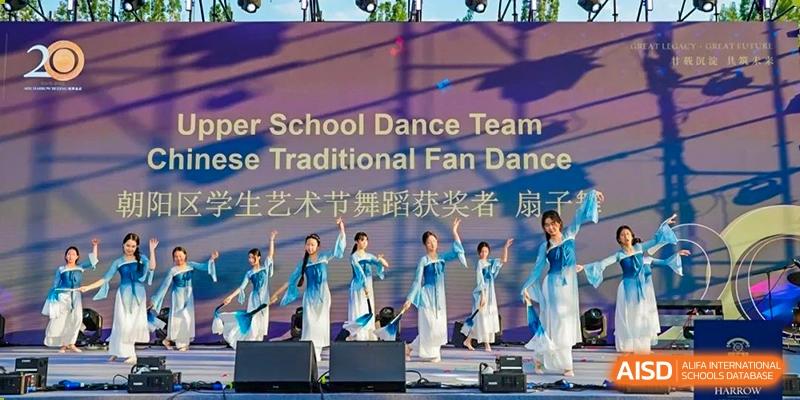 The Harrow International School Beijing (AISL Beijing) Upper School Dance Team performs a Chinese Traditional Fan Dance on stage.