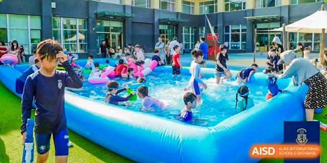 Young children from Harrow International School Beijing (AISL Beijing) are splashing and playing in a large inflatable pool.