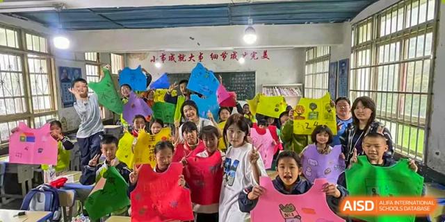 A large group of smiling students wearing colorful plastic helmets or headgear during a fun event or competition at BEIJING CHAOYANG TONGWEN FOREIGN LANGUAGE SCHOOL.