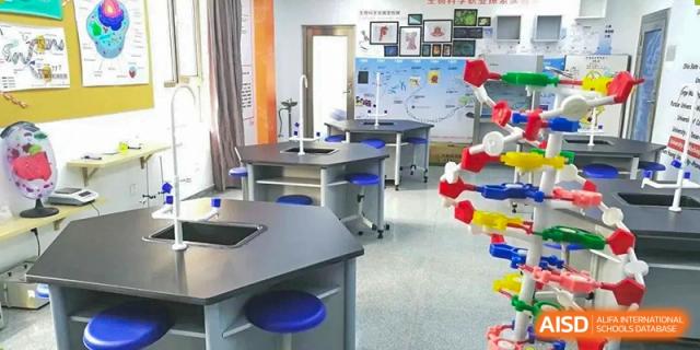 A bright science or makerspace classroom at BEIJING CHAOYANG TONGWEN FOREIGN LANGUAGE SCHOOL with hexagonal worktables and blue stools.