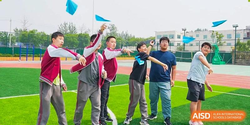 A small group of students raising flags or cheering during a sports event outdoors at BEIJING CHAOYANG TONGWEN FOREIGN LANGUAGE SCHOOL.