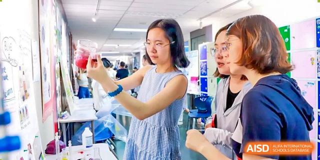 A photo showing a female student performing a scientific experiment in a lab, at Beijing Foreign Studies University International Curriculum Center.