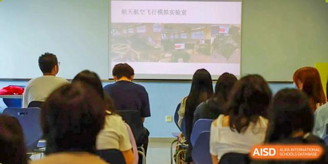A photo showing a teacher explaining something to students in a classroom, at Beijing Foreign Studies University International Curriculum Center.