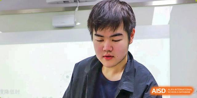 A photo showing a male student sitting at a desk, at Beijing Foreign Studies University International Curriculum Center.