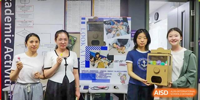 A photo showing a teacher standing with a student with some kind of display, at Beijing Foreign Studies University International Curriculum Center.