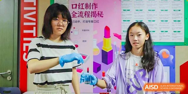 A photo showing a teacher and a student standing with a board, at Beijing Foreign Studies University International Curriculum Center.