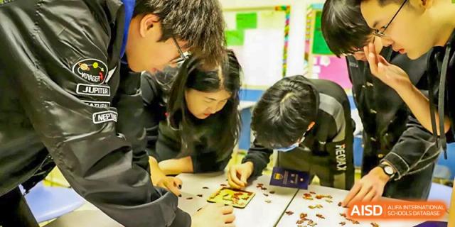 A photo showing a group of students sitting on the floor and doing some kind of activity, at Beijing Foreign Studies University International Curriculum Center.