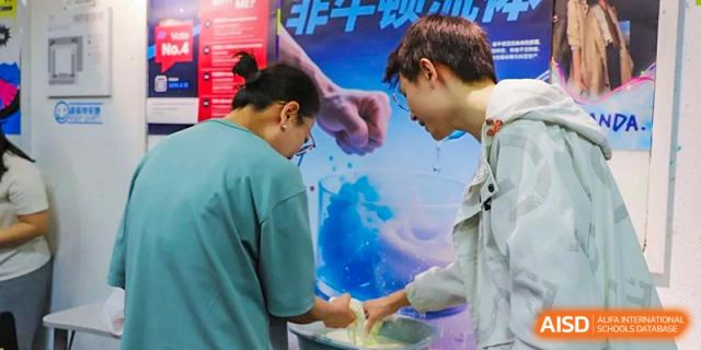 A photo showing a group of students in a lab, doing a medical experiment with liquids, at Beijing Foreign Studies University International Curriculum Center.