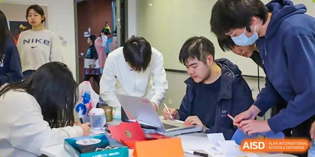 A photo showing a group of male students sitting at a desk and studying, at Beijing Foreign Studies University International Curriculum Center.