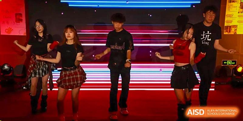 A photo showing students performing on a stage. They are performing some kind of dancing and musical show, at Beijing Foreign Studies University International Curriculum Center.