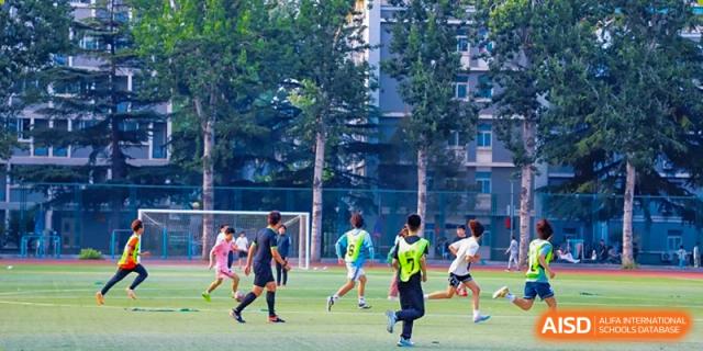 A photo showing students playing football on a playground, at Beijing Foreign Studies University International Curriculum Center.