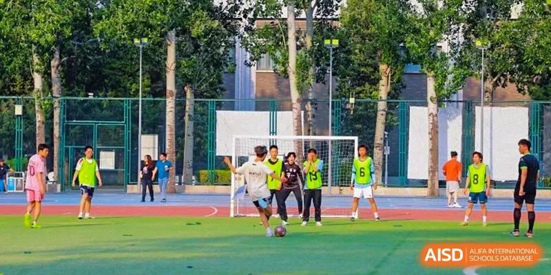 A photo showing students playing football on a football ground, at Beijing Foreign Studies University International Curriculum Center.