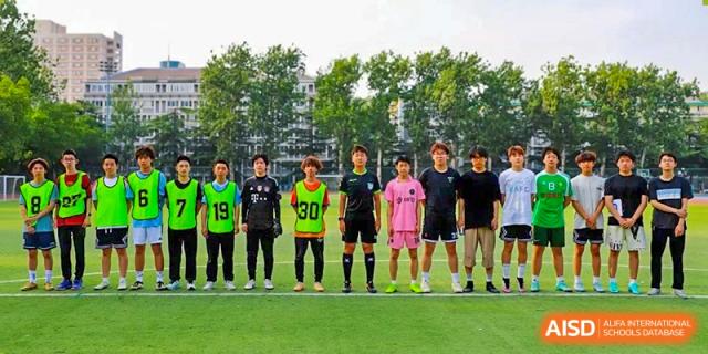 A photo showing a football team posing for a group photo on a field, at Beijing Foreign Studies University International Curriculum Center.