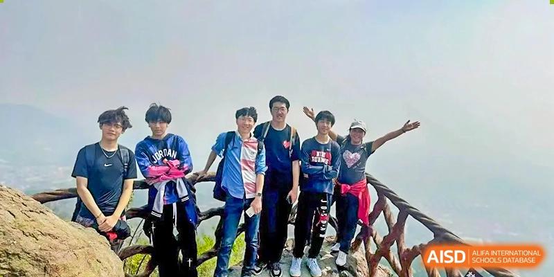 A photo showing a group of students posing in front of their bikes for a photo, at Beijing Foreign Studies University International Curriculum Center.