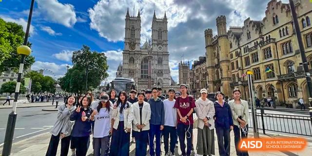A photo showing a large group of students posing for a group photo in front of a church, at Beijing Foreign Studies University International Curriculum Center.