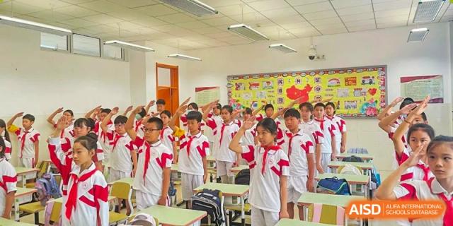 A large group of students from Shijingshan School of The High School Affiliated to Renmin University of China stands together in a classroom.