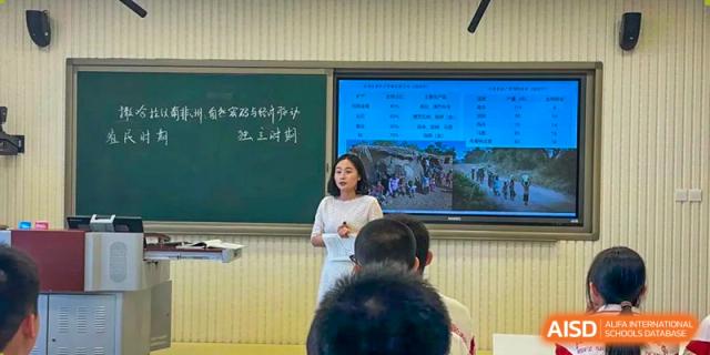 Students from Shijingshan School of The High School Affiliated to Renmin University of China watch a presentation by a teacher on a large screen.