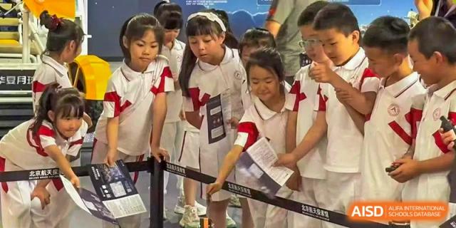 Students from Shijingshan School of The High School Affiliated to Renmin University of China stand in a museum or science exhibition.